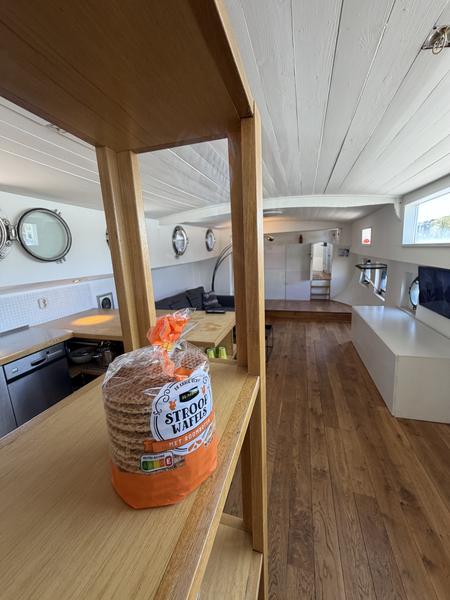 This photo captures a warm and inviting interior, likely a houseboat, with a package of Stroopwafels prominently displayed on a wooden shelf